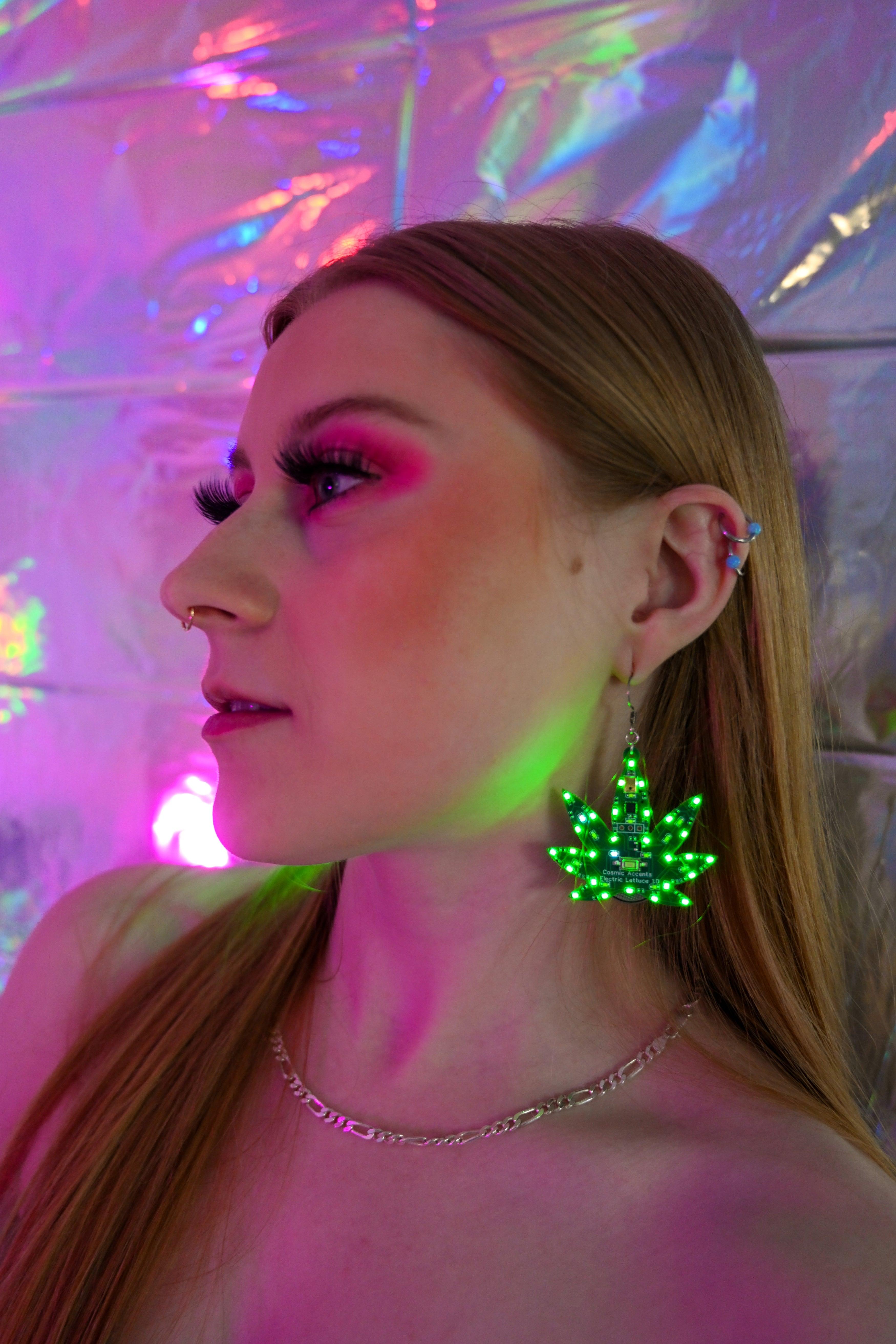 A young woman wearing marijuana-shaped LED earrings and a simple necklace.
